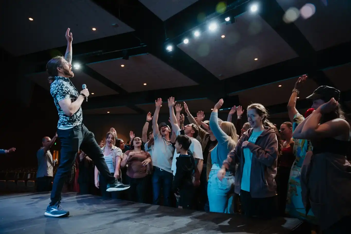 Serve team gathered at the front of the auditorium with hands raised